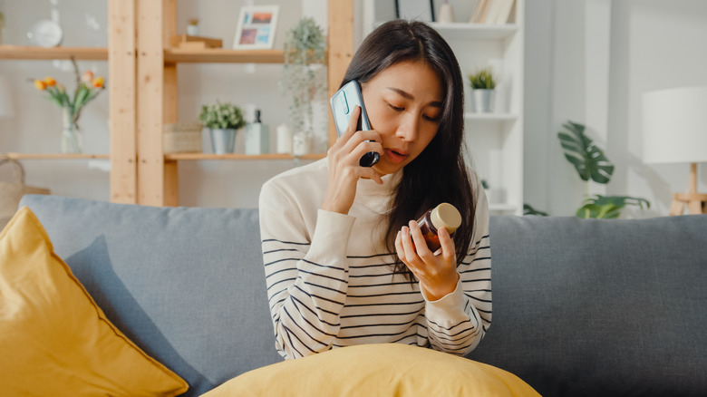 Woman on phone holding pill bottle 